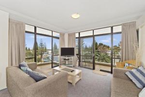 a living room with a television and large windows at Tasman Towers 9 3 Munster Street Port Macquarie in Port Macquarie