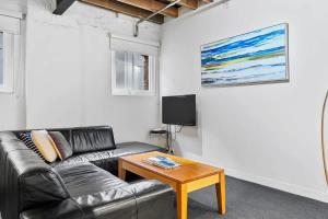 a living room with a leather couch and a table at Gibson Mill waterfront warehouse apartment - 102 in Hobart +11 photos