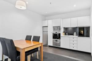 a kitchen with a wooden table and black chairs at Gibson Mill waterfront warehouse apartment - 104 in Hobart