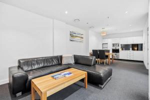 a living room with a black leather couch and a table at Gibson Mill waterfront warehouse apartment - 104 in Hobart