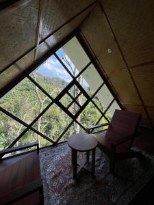 a chair and stool in a room with a large window at Lush Acres in Thekkady