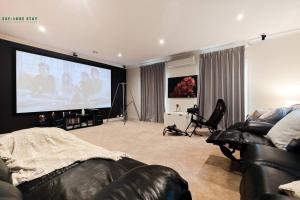 - un salon avec un grand écran dans l'établissement Balwyn Luxury 5BR Mansion with Cinema & BBQ, à Melbourne