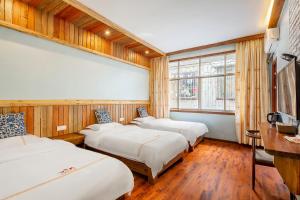 Zimmer mit 3 Betten, einem Schreibtisch und Fenstern in der Unterkunft Breeze Alley Inn--English reception-Tourism planing in Zhangjiajie