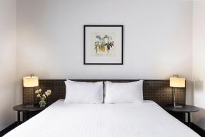 Un dormitorio con una cama blanca con dos lámparas. en Edit Auckland Central, en Auckland