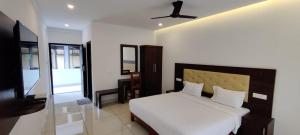 a bedroom with a bed and a flat screen tv at Hotel Trees Thekkady in Thekkady