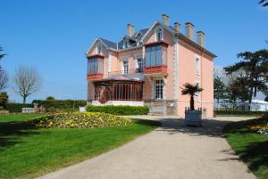 una gran casa rosa con un camino delante de ella en Gite les Flots Bleus, en Jullouville-les-Pins