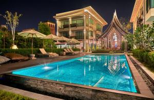 a swimming pool in front of a house at night at Maraya Hotel & Resort -SHA Plus in Chiang Mai