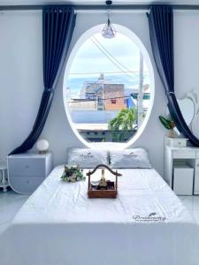 a bedroom with a large window and a white bed at Hoàng Nga 1 Homestay in Phan Thiet