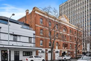 ein großes Backsteingebäude mit davor geparkten Autos in der Unterkunft Gibson Mill waterfront warehouse apartment - 103 in Hobart