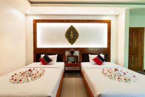 two beds in a room with white and red pillows at Peak Elite Boutique in Siem Reap