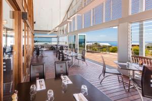 a restaurant with tables and chairs and a view of the ocean at Silverwater Resort Phillip Island in San Remo