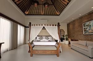 a bedroom with a canopy bed and a couch at HomeSix Bali in Uluwatu