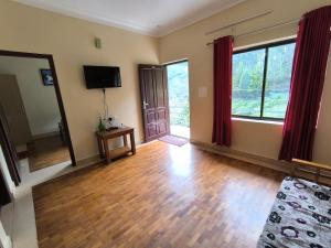 an empty living room with wooden floors and windows at Mountain Hut Vattavada Resort in Munnar