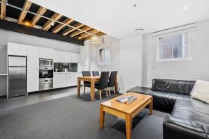 a living room with a black leather couch and a table at Gibson Mill waterfront warehouse apartment - 202 in Hobart