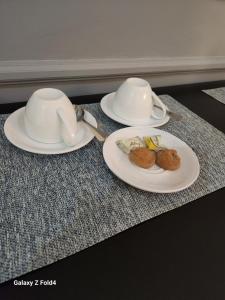 two plates and cups on a table with food on them at Sunshine Inn in Gaborone