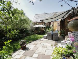 a patio with chairs and an umbrella in a garden at The Old Byre in Salisbury