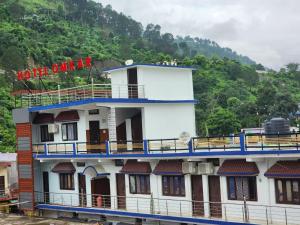 a large white building with a mountain in the background at Hotel Omkaar & Restaurant Chinyalisaur in Chhām