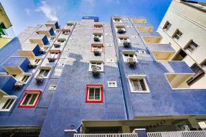 LingampalliFabExpress Grand Aarvi Prime - Nr GSM Mall, Madeenaguda的一座高大的蓝色建筑,设有红色窗户