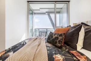 ein Schlafzimmer mit einem Bett mit Kissen und einem großen Fenster in der Unterkunft West Side Spencer St Apt w Marvel Stadium View in Melbourne + 21 Fotos