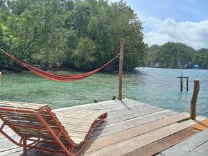 a hammock sitting on a dock on a lake at Pin Wawiyai Natural Homestay in Yennanas Besir +6 photos