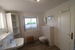 a bathroom with a sink and a toilet and a window at Ferienwohnung bei Antje Timm in Hiddensee