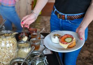 a woman holding a plate with a sandwich on a table at Langley Hôtel Le Petit Prince in L'Alpe-d'Huez +20 photos
