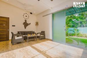 a living room with chairs and a table and a clock at Sundream Palms by VEO - Part of StayVista with Pool, Lawn, BBQ in Alibag