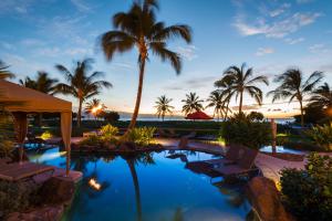 a resort pool with chairs and palm trees at dusk at Honua Kai Hokulani 825 in Lahaina
