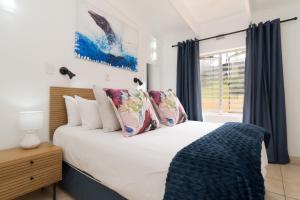 una camera da letto con un letto bianco con cuscini e una finestra di Chakas Rock Chalets 49 a Ballito