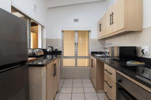 una grande cucina con armadi in legno e ripiani neri di Chakas Rock Chalets 49 a Ballito