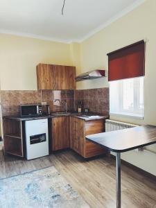 a kitchen with wooden cabinets and a table in it at Tolqyn apart hotel in Aktau +4 photos