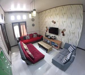 a living room with a red couch and a tv at Omah Wirokerten Syariah Homestay Jogja in Gondowulung