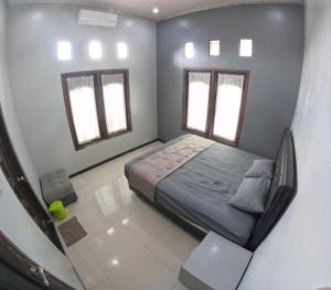 a small bedroom with a bed and two windows at Omah Wirokerten Syariah Homestay Jogja in Gondowulung