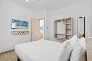 Un dormitorio blanco con una cama blanca y una ventana. en Caya Erasmus 5, en Oranjestad 37 fotos más