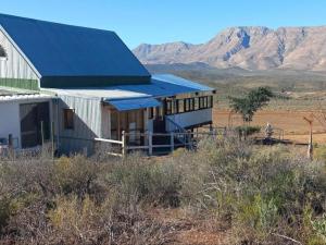 a building with a blue roof with mountains in the background at Botterboom - Private Karoo Campsite in Barrydale