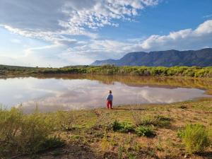a person standing in front of a body of water at Botterboom - Private Karoo Campsite in Barrydale