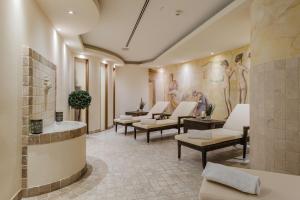 a waiting room with white chairs and paintings on the wall at Hotel Mondial am Dom Cologne MGallery in Cologne