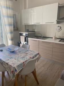 Le Dimore del Mare في توري كان: مطبخ مع طاولة وكراسي ومطبخ مع دواليب بيضاء