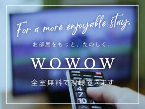 a person holding a remote control in front of a television at Hotel Route-Inn Susono Inter in Susono