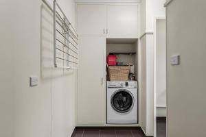 Un lavadero blanco con lavadora y secadora. en Cute Retro Gem, en Geelong