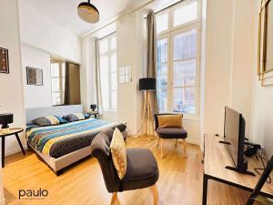 a bedroom with a bed and a tv and a chair at Studio chaleureux in Laon