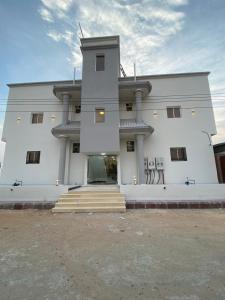 a large white building with stairs in front of it at Evora إيفورا in Sharurah