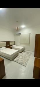 a room with two beds and a rug at Evora إيفورا in Sharurah