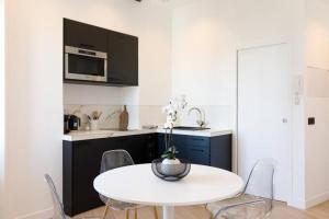 een witte keuken met een witte tafel en stoelen bij Appartement 33 m2 comme une junior suite - vue Port et Palais des festivals in Cannes