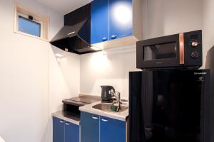 Elle comprend une petite cuisine avec des placards bleus et un four micro-ondes. dans l'établissement Hotel SALIFORT HAKATA, à Fukuoka