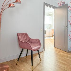 a pink chair sitting against a wall in a room at City heart, space, loft view, free parking in Rīga