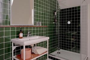 a green tiled bathroom with a sink and a shower at ALFRED HOTELS Compiègne in Compiègne