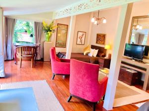 a living room with pink chairs and a couch at Ban Kaew Villas in Bophut 