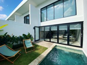 a house with a swimming pool and two chairs at Canggu 2Plex Apartment in Canggu