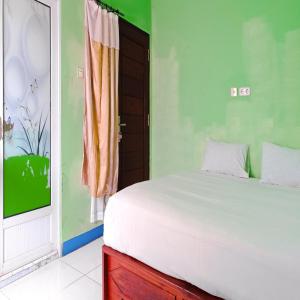 Un dormitorio con una cama blanca y una ventana. en Hotel Pabelan RedPartner, en Bengkulu